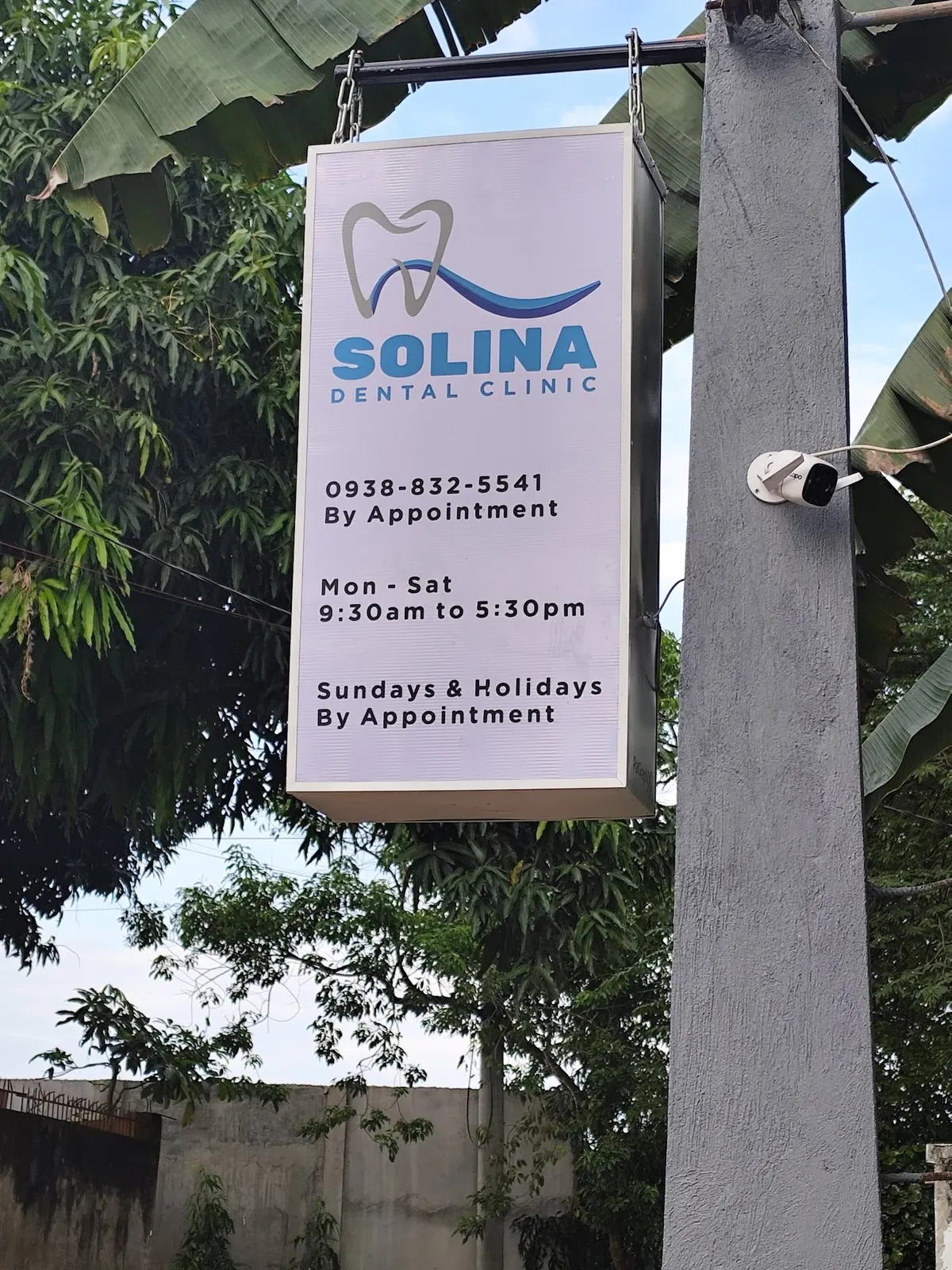 The hanging Solina Dental Clinic sign listing Mon–Sat 9:30am to 5:30pm, by appointment